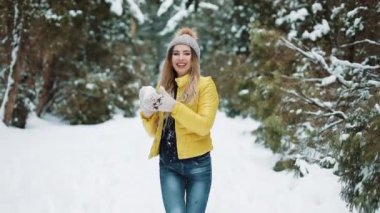 Çekici kız ormanda kartopu oynuyor. Kış aylarında açık havada eğleniyor kamera aktif genç kadın isthrowing topu