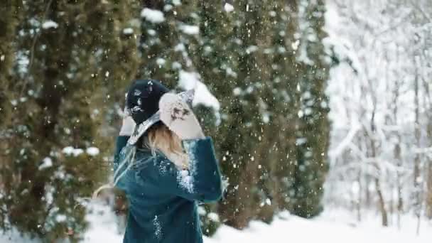 Lady in groen hoed en vacht wervelingen onder de vallende sneeuw in het bos — Stockvideo