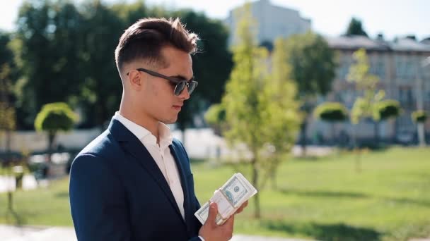 Joven hombre de negocios con dinero. Un hombre exitoso está feliz por el dinero. El dinero no huele. Negocios exitosos. Disparo en la épica roja — Vídeo de stock