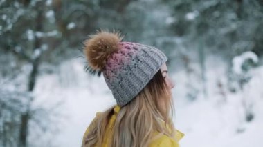 Genç ve güzel kadın bir kış orman yürür ve omuz gülümsediğini üzerinde görünüyor