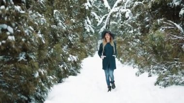 Arkadan Bayan yeşil şapka ve bir kış orman yürüyüş bir kat bak. Kız görünüyor ve kameraya poz veriyor