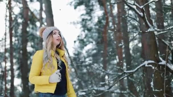 Hübsche junge Frau in gelber Jacke läuft durch einen Winterwald — Stockvideo