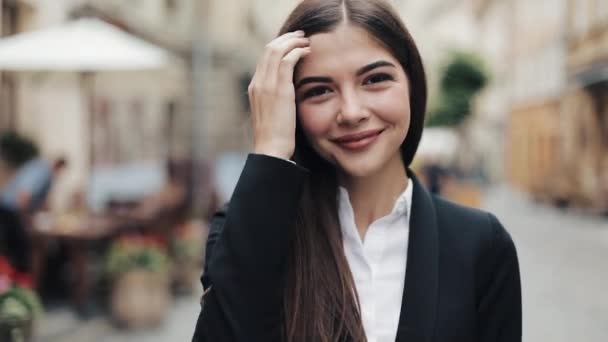 Young business woman walks down the central city street, turns and smiles right to the camera, posing and playing with her long hair. Being emotional, cheerful mood — Stock Video
