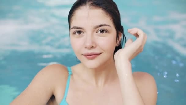 Jovem mulher sexy em maiô azul posando na piscina com água azul-turquesa — Vídeo de Stock