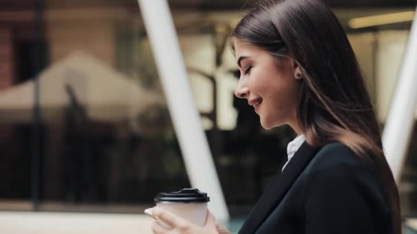 Joven empresaria profesional que camina por la calle urbana con un smartphone y bebe café. Concepto: nuevo negocio, comunicación, banquero. Afuera, cámara lenta — Vídeos de Stock