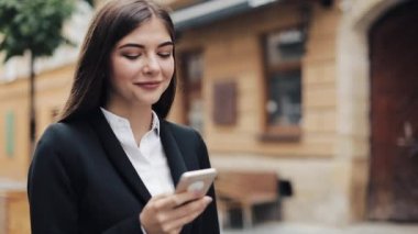 Smartphone kullanarak ve eski sokakta yürüyen genç güzel iş kadını. İnternette sörf. Konsept: yeni iş, iletişim, bankacı, Yöneticisi