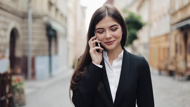 Prachtige jonge zakenvrouw gelukkig praten op haar telefoon, wandelen, lacht. Zakelijke lifestyle, actieve levensstijl, moderne vrouw. Vrolijke stemming — Stockvideo