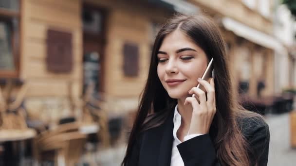 Prachtige jonge zakenvrouw gelukkig praten op haar telefoon, wandelen, lacht. Zakelijke lifestyle, actieve levensstijl, moderne vrouw. Vrolijke stemming — Stockvideo