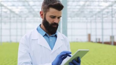 Dijital tablet üzerinde çalışan sera içinde ziraat mühendisi portresi. Yakın çekim