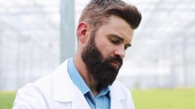 Araştırmacı bir sonda yeşil bitki alır ve bir kabında koyar. Serada çalışan ziraat mühendisi