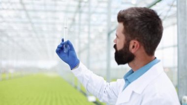 Araştırmacı bir sera bir tüp ayakta su alır. Ziraat Mühendisi analizi, mühendislerimizin bitkiler yapar