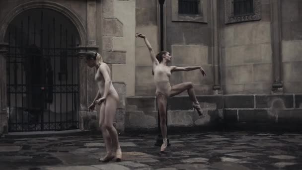 Jóvenes bailarinas profesionales están realizando danza acrobática a lo largo de la calle medieval bajo la lluvia. Chicas mojadas bailando en gotas de agua, cámara lenta — Vídeos de Stock