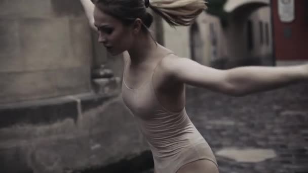 De jeunes danseuses professionnelles exécutent une danse acrobatique le long de la rue médiévale sous la pluie. Les filles humides dansent dans des gouttes d'eau, au ralenti — Video