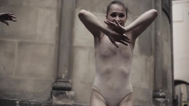 Mladí profesionální tanečnice provádí akrobatické tanec podél středověké ulice pod deštěm. Vlhké dívky tančí v kapky vody, pomalý pohyb — Stock video