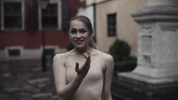 Young professional female dancer is performing acrobatic dance along the medieval street under the rain. Ballerina dancing in water drops, slow motion — Stock Video