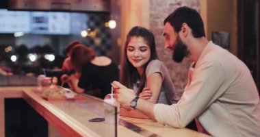 Café'de akşam geç Smartphone kullanarak çekici genç bir çift. Arkadaşlar, iletişim, çıkan, sohbet anlayışı çiftin,