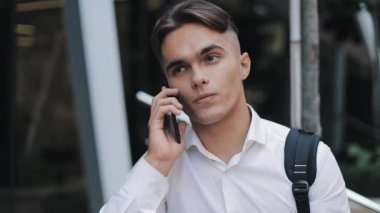 Mutlu ypung işadamı telefonu konuşurken bir sırt çantası ile. Modern Ofis Binası yakınındaki ayakta. Konsept: teknoloji, telefon, iş gezileri, iş