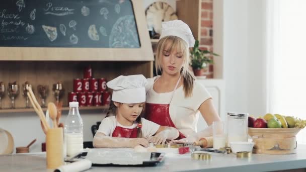 ママと同じ服を娘は、居心地の良いキッチンに生地を準備して楽しい時を過します。彼らはクリスマスのクッキーを準備しています。家族の日、料理、ママと娘のコンセプト — ストック動画