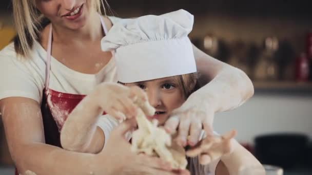 Moeder en dochter in dezelfde kleren veel plezier bereiden een deeg op een gezellige keuken. Ze bereiden zich kerstkoekjes. Familie dag, koken, moeder en dochter concept — Stockvideo