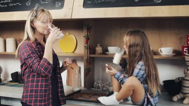 Gelukkige familie. Meisje met haar moeder eten melk en koekjes in de keuken, calcium, Ontbijt, gezondheid. Slow-motion — Stockvideo