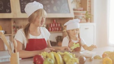 Anne ve küçük kızı mutfakta yemek: Onlar taze bir bahçe salata ve anne kız öğretir. Pişirme ve mutlu aile kavramı