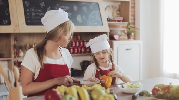 Moeder en dochtertje koken in de keuken: ze maken een frisse tuin salade, en moeder leert het meisje. Koken en gelukkige familie concept — Stockvideo