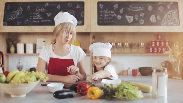 Maman et petite fille cuisinent dans la cuisine : elles font une salade de jardin fraîche, et la mère enseigne à la fille.Cuisine et concept de famille heureuse — Video