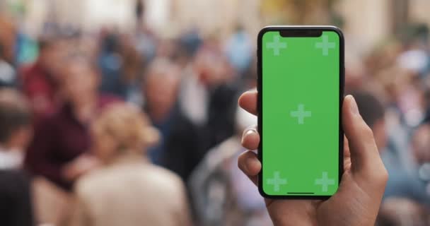 关闭拍摄男子手拿着智能手机与绿色屏幕在城市街道背景。色度键 — 图库视频影像