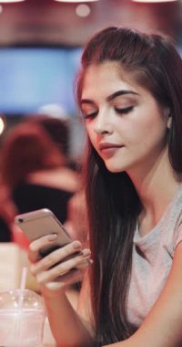 Dikey Video. Neon tabela yakınındaki bir telefon numarası çevirmeden oturan güzel genç bir kadının yakın çekim. Sosyal ağ dikey video kullanıma hazır