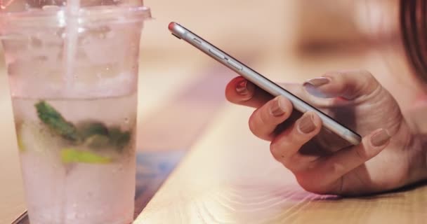 Imagem de close-up da mão feminina digitando mensagem SMS. Mulher sentada em bar ou restaurante — Vídeo de Stock