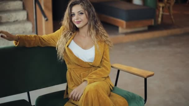 Bonita jovem empresária posando na câmera, sorrindo, sentado no sofá no aconchegante café Sucesso, beleza, conceito de mulher feliz — Vídeo de Stock