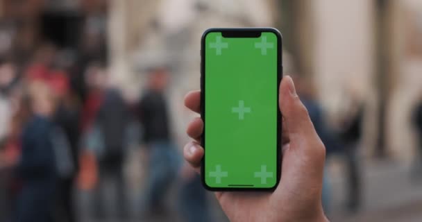 Closeup bir el bir cep telefonu dikey yeşil bir ekran ile sokaklarda tutarak mans — Stok video