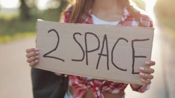 年轻的美女搭便车站在路上, 拿着两个空间标志。夏季时间 — 图库视频影像
