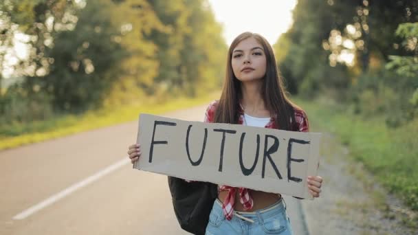 Junge schöne Frau trampt auf der Straße stehend mit einem Zukunftsschild. Sommerzeit — Stockvideo