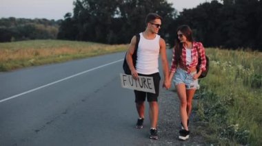 Yolda otostop ve gelecekteki işareti tutarak tatile çift. Yaz saati. Kavramı, turistler, otostop Maceraları.