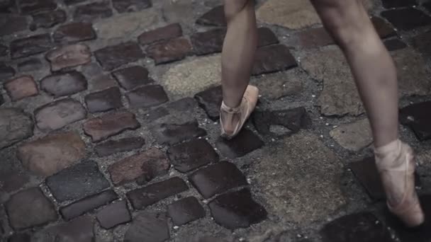 Elegante joven bailarina de ballet medieval calle bajo la lluvia. Dando un paso en puntas de los pies en punta. El primer plano de las bailarinas por las piernas. Movimiento lento — Vídeo de stock