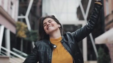 Sokakta yürüyen ve dans hareketli mutlu genç kadın. Ağır çekim
