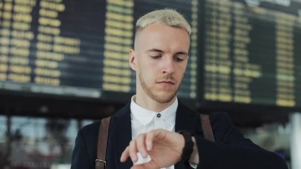 공항에서 출발 라운지에서 탑승을 기다리는 매력적인 젊은 사업가. 그는 스마트 시계 보고 — 비디오