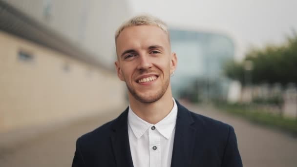 Retrato de guapo feliz hombre de negocios sonriente de pie cerca del edificio de oficinas — Vídeos de Stock