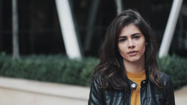 Retrato facial de una atractiva mujer de pie en la calle moderna. Mujer sonriendo. Chaqueta de cuero negro — Vídeo de stock