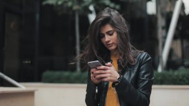 Şehrin smartphone kullanırken sokak yürüyen genç mutlu kadın. Ağır çekim