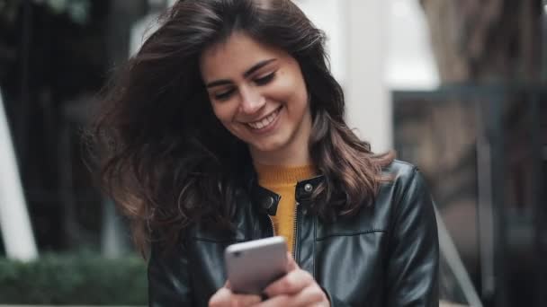 Giovane donna felice passeggiando per la strada della città durante l'utilizzo di smartphone. Rallentatore — Video Stock