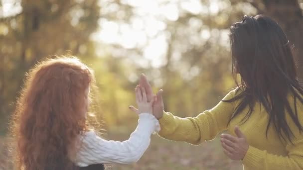 Mãe e filha mãos brincando. Família feliz no parque de outono — Vídeo de Stock