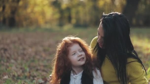 Schattig klein meisje haar moeder knuffelen in de herfst park. Gelukkige familie concept — Stockvideo