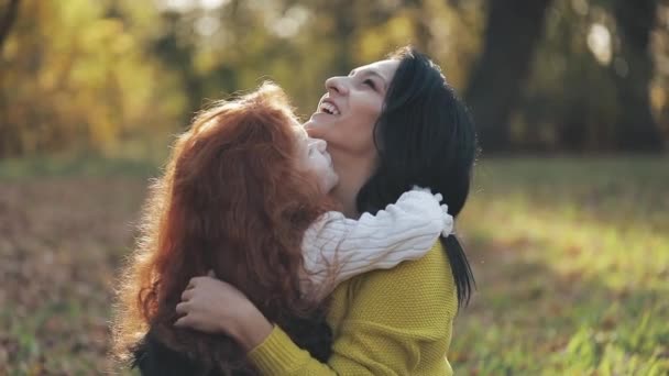 Schattig klein meisje haar moeder knuffelen in de herfst park. Gelukkige familie concept — Stockvideo