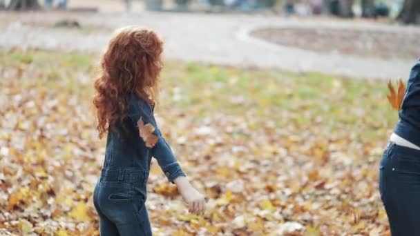 Happy mother and her Little daughter having fun in autumn park. Young family throwing leaves and laughing. Slow-motion — Stock Video