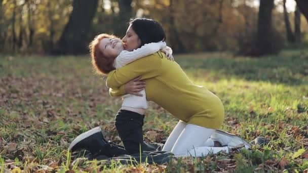 Máma a dcera hraje v podzimním parku, budou jíst a smíchu. pomalý pohyb — Stock video