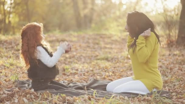 Una madre felice e una figlioletta carina sedute insieme e che giocano con la mela in un parco cittadino durante un picnic. Ora di autunno — Video Stock