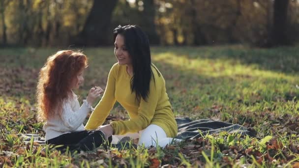 Mamá y su hija jugando en el parque de otoño, Comen, riendo y sonriendo. cámara lenta — Vídeos de Stock