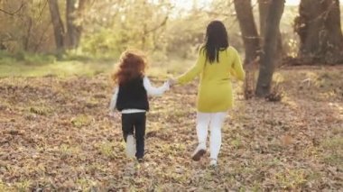Mutlu genç anne ve onun küçük kızıl saçlı kızı runing birlikte sonbahar bir park. Onlar gülen ve having fun elele. Ağır çekim